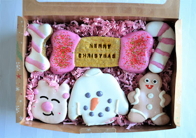 A box of decorated doggy treats including iced bones, candy canes, and snowman